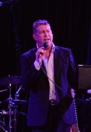 Randy McCallister performing on stage under purple lighting